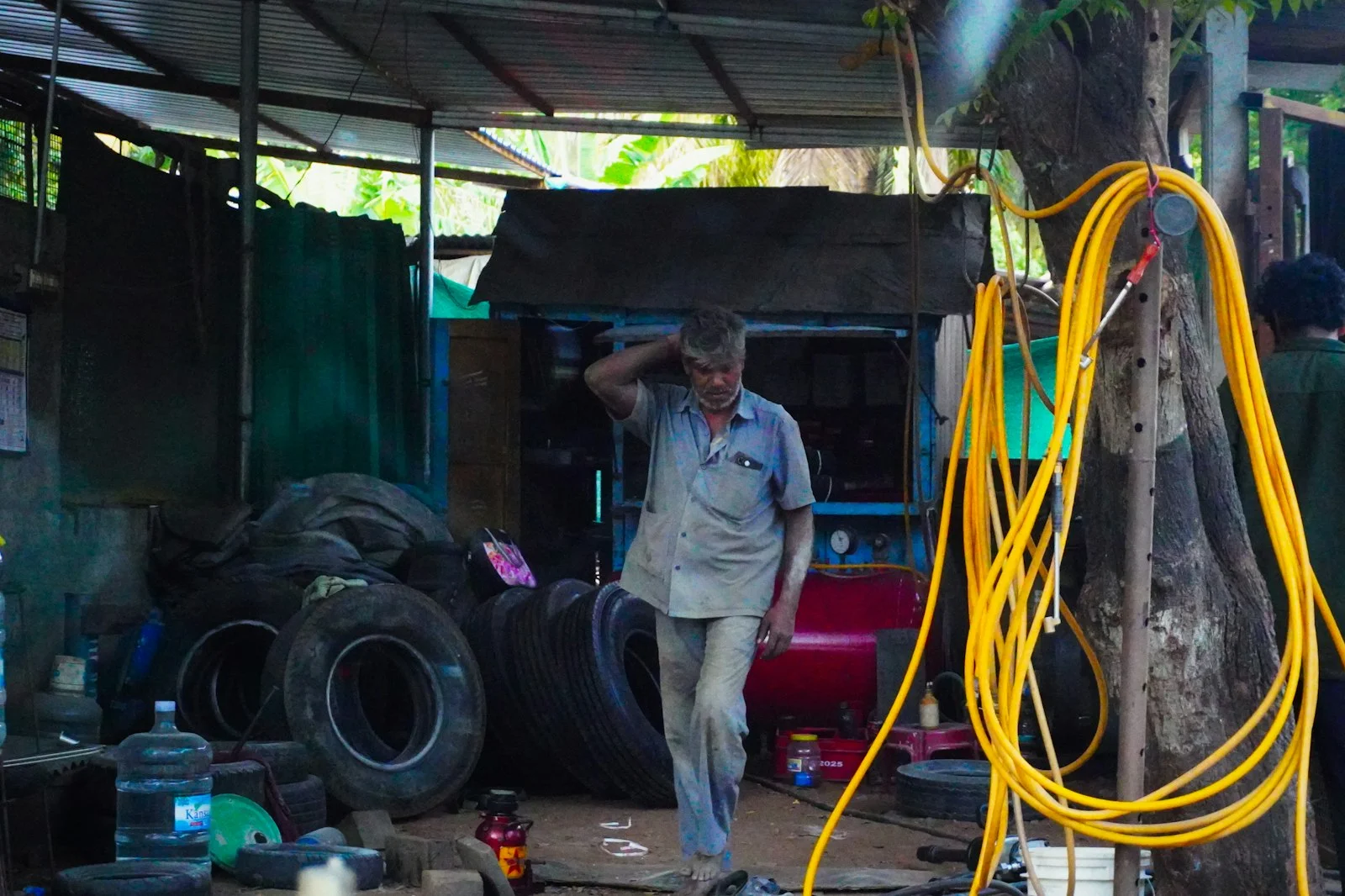 Man walks through a tire shop with stacked tires.