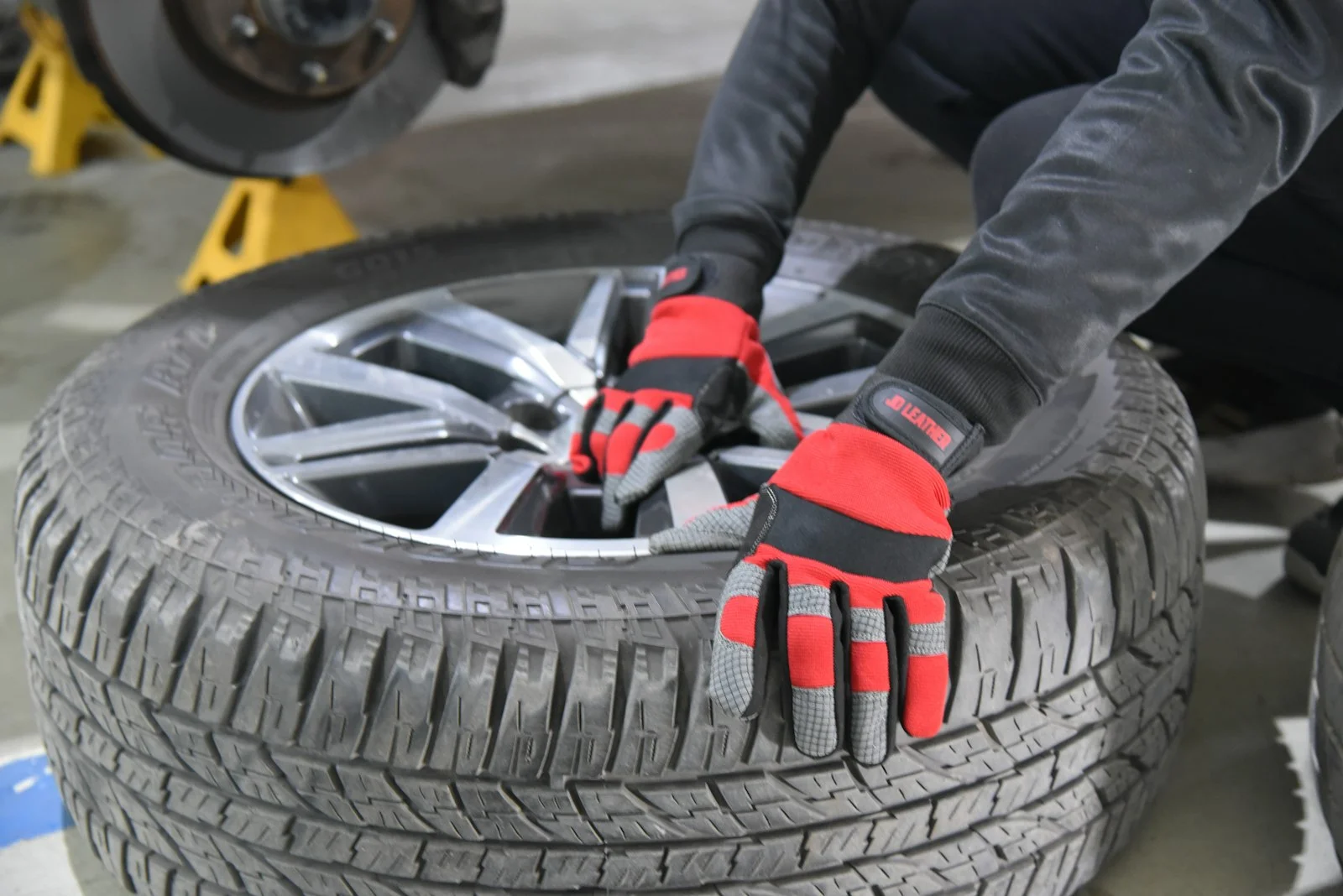 A person wearing red gloves works on a car tire A person wearing red gloves works on a car tire